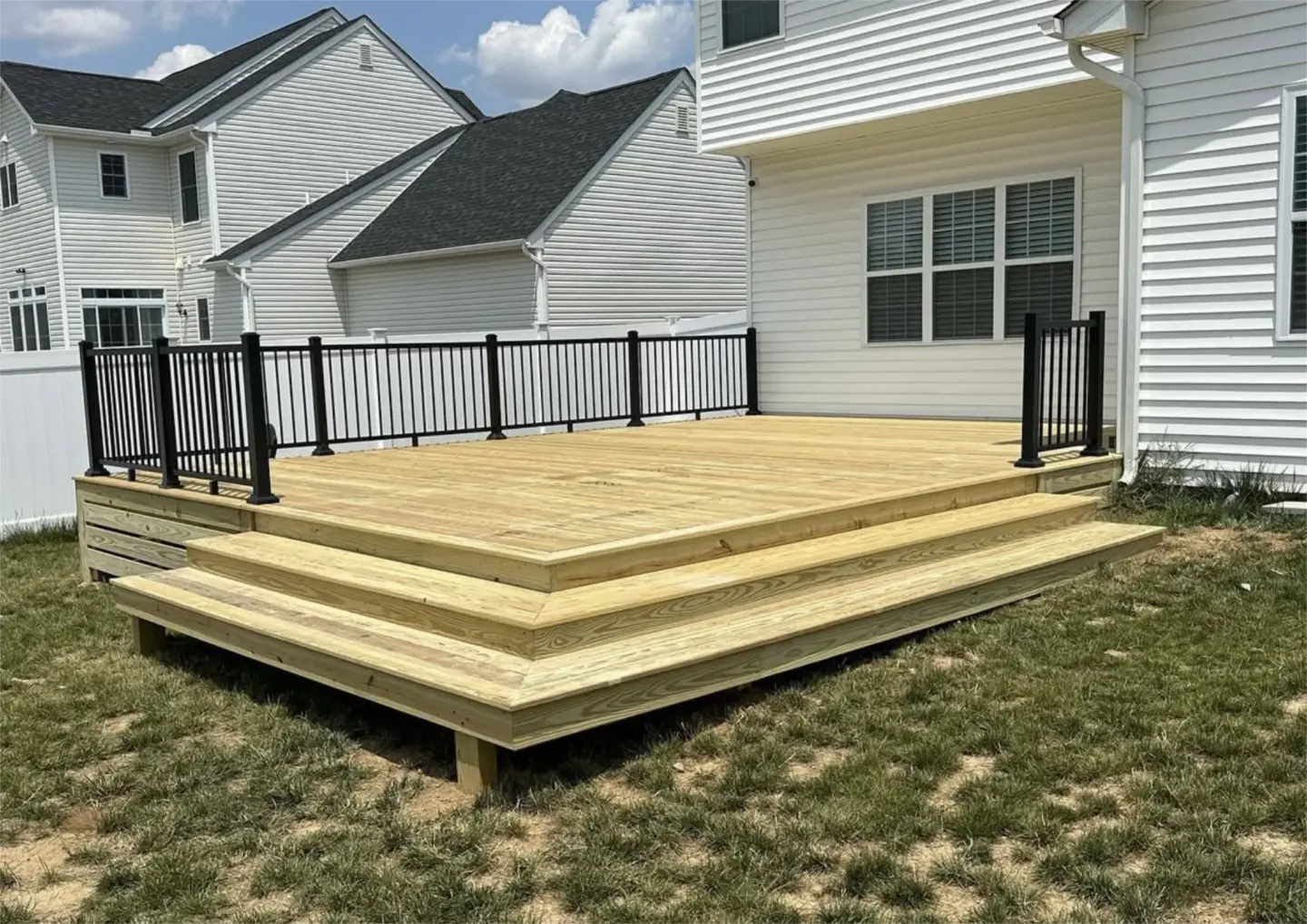 Backyard wooden deck with black railings and wide steps