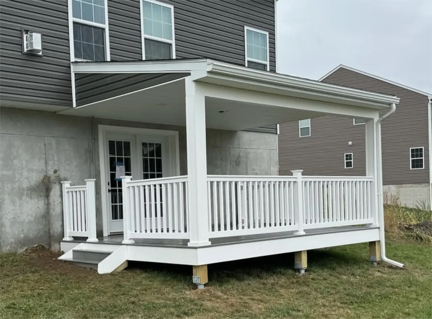 Covered backyard deck with white railing and sloped roof.
