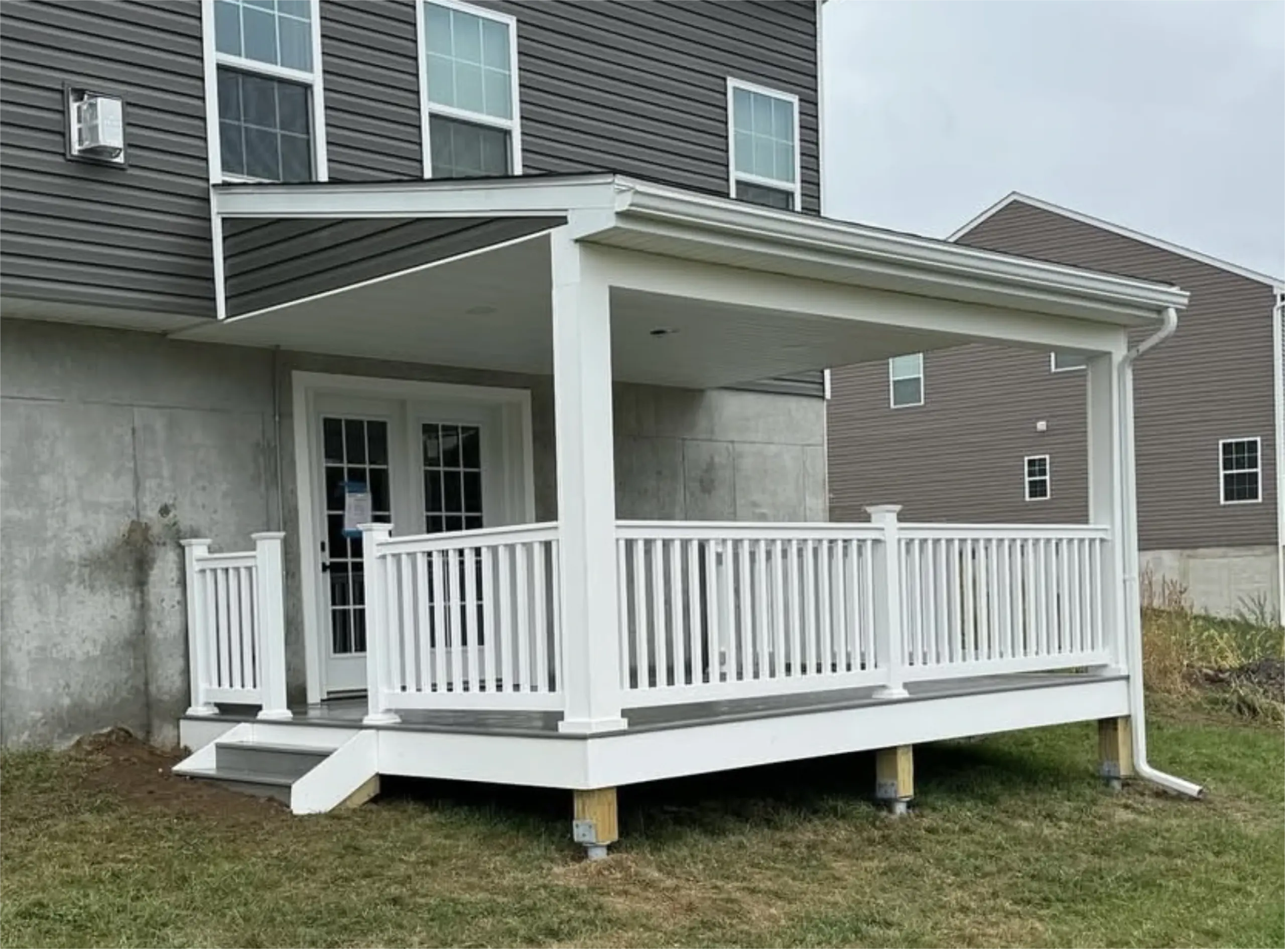 Covered backyard deck with white railing and sloped roof.