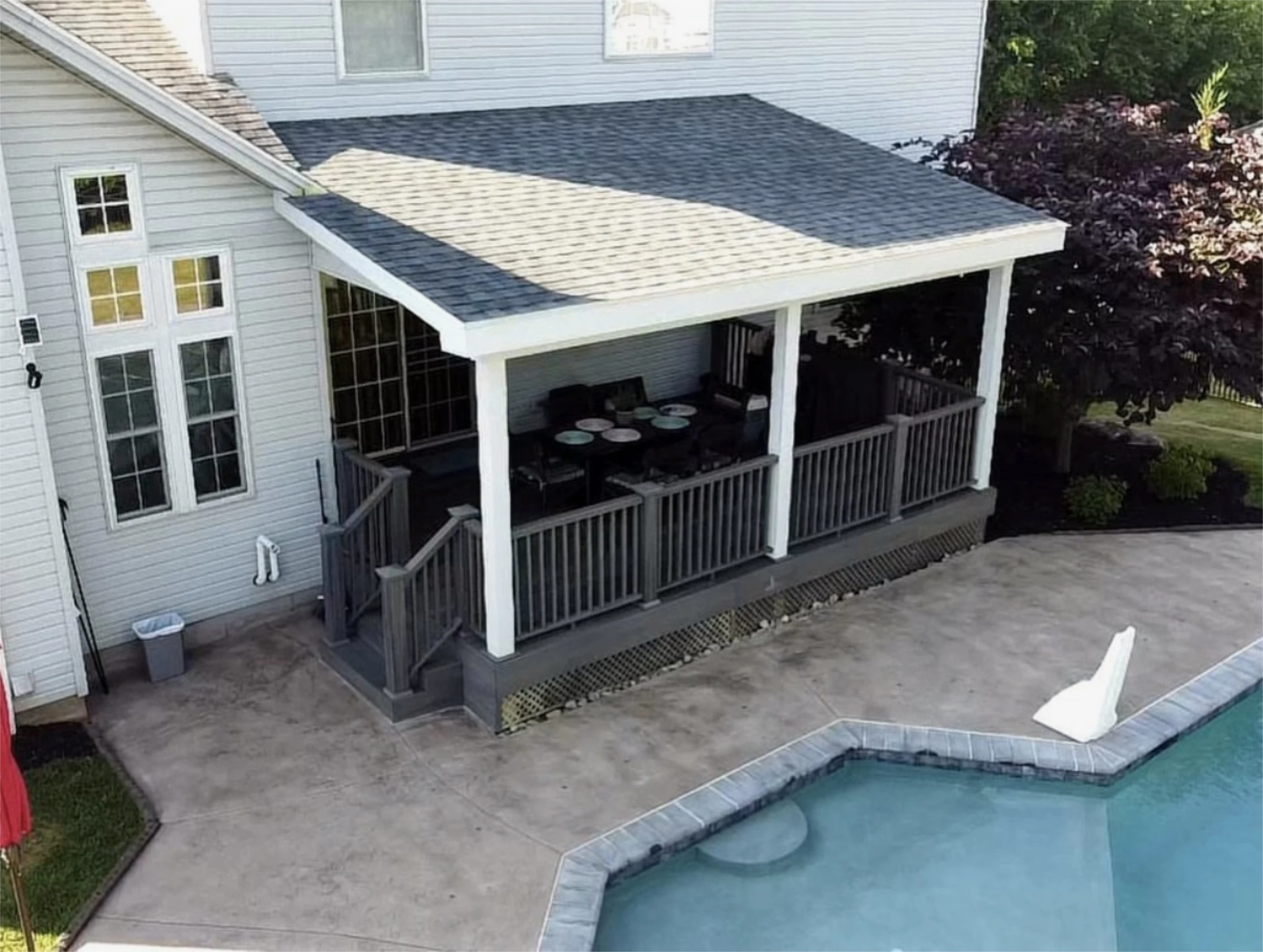 Covered backyard patio beside pool and house.