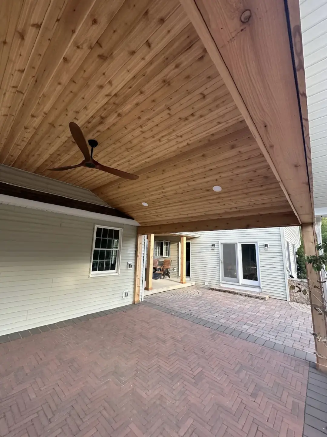 Covered patio with cedar ceiling and brick pavers.