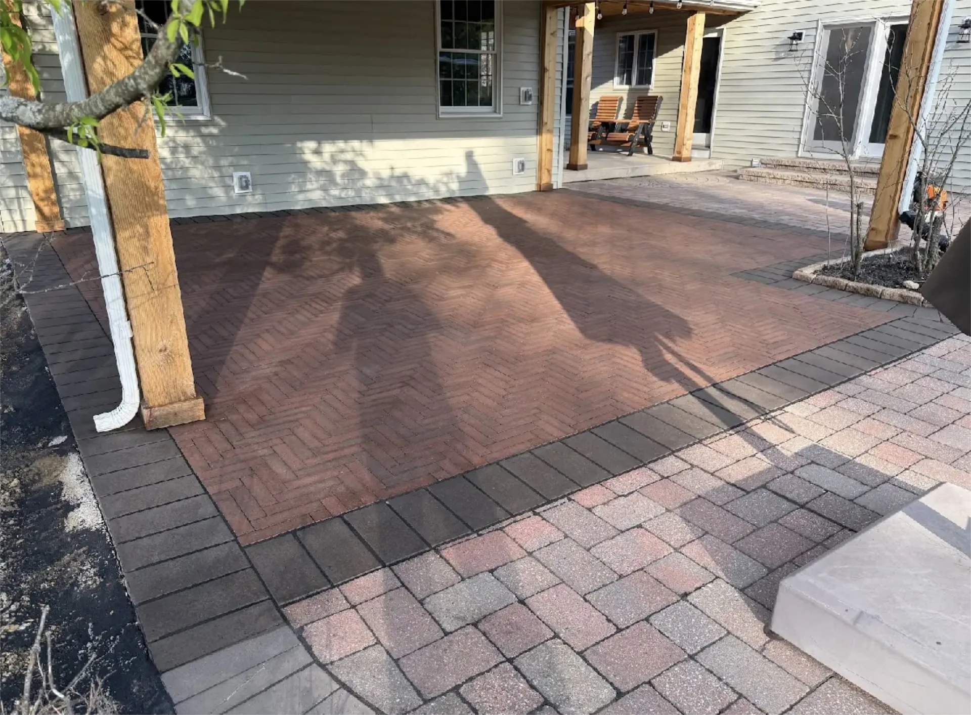 Covered patio with herringbone brick inlay and multicolor paver border.