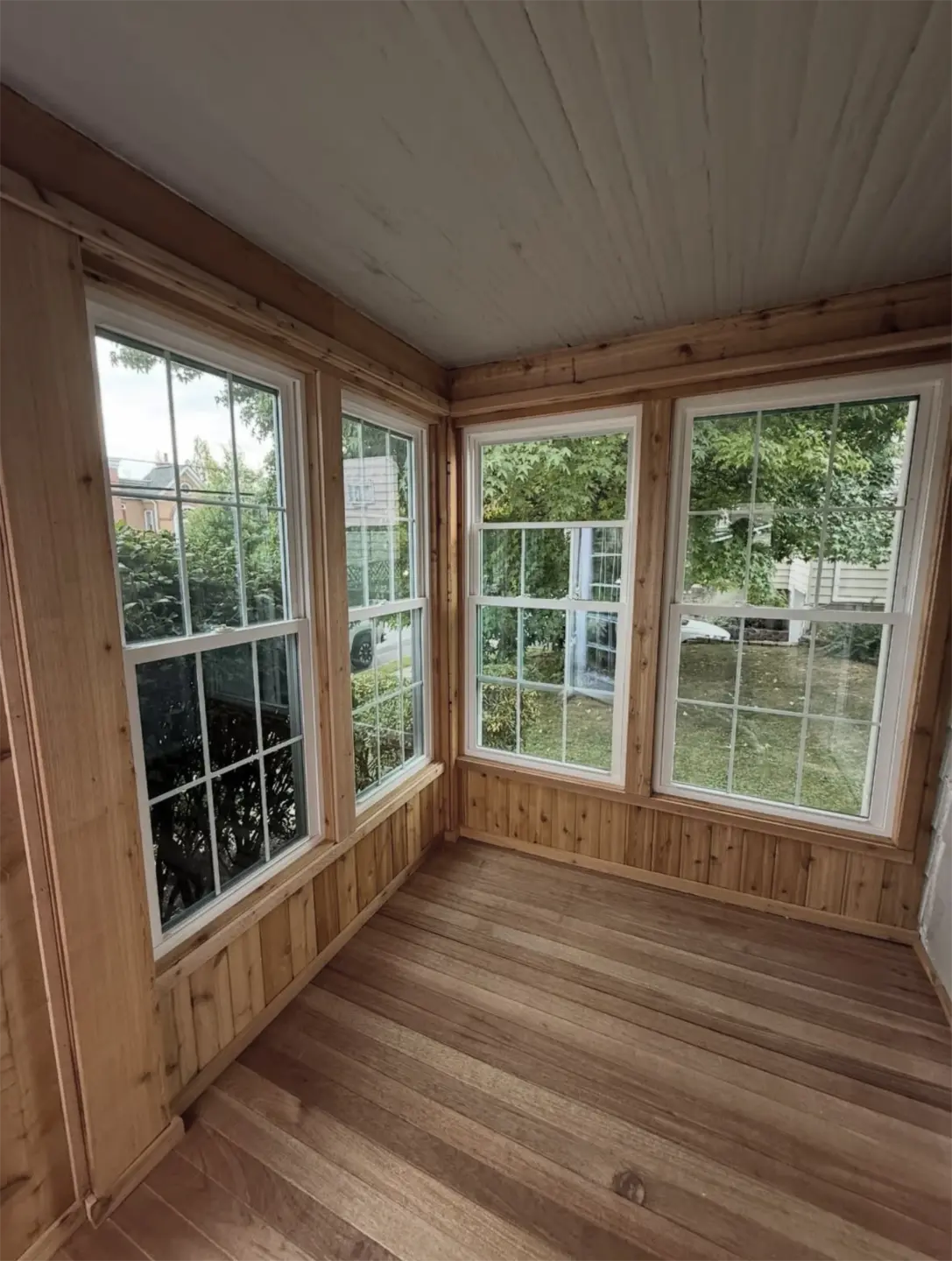 Cozy wood sunroom with wicker chairs and large windows.