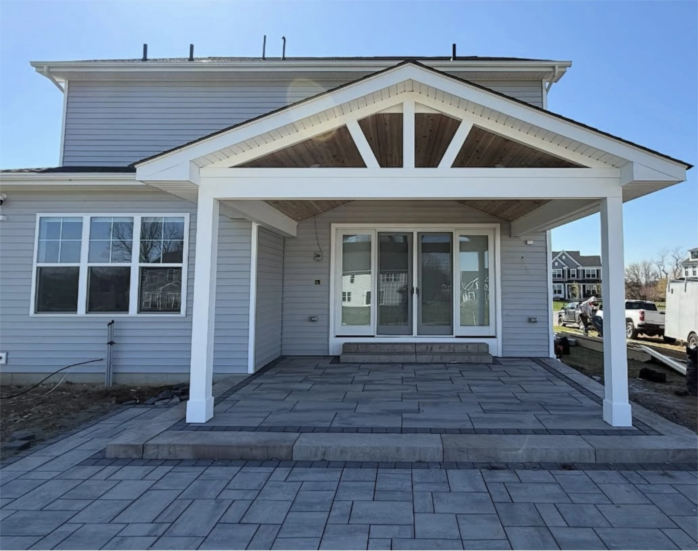 Gabled covered patio with wood ceiling and sliding doors.