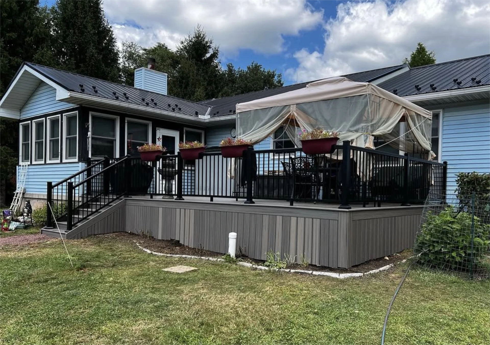 “Ground level composite deck with black railings and outdoor canopy seating.”