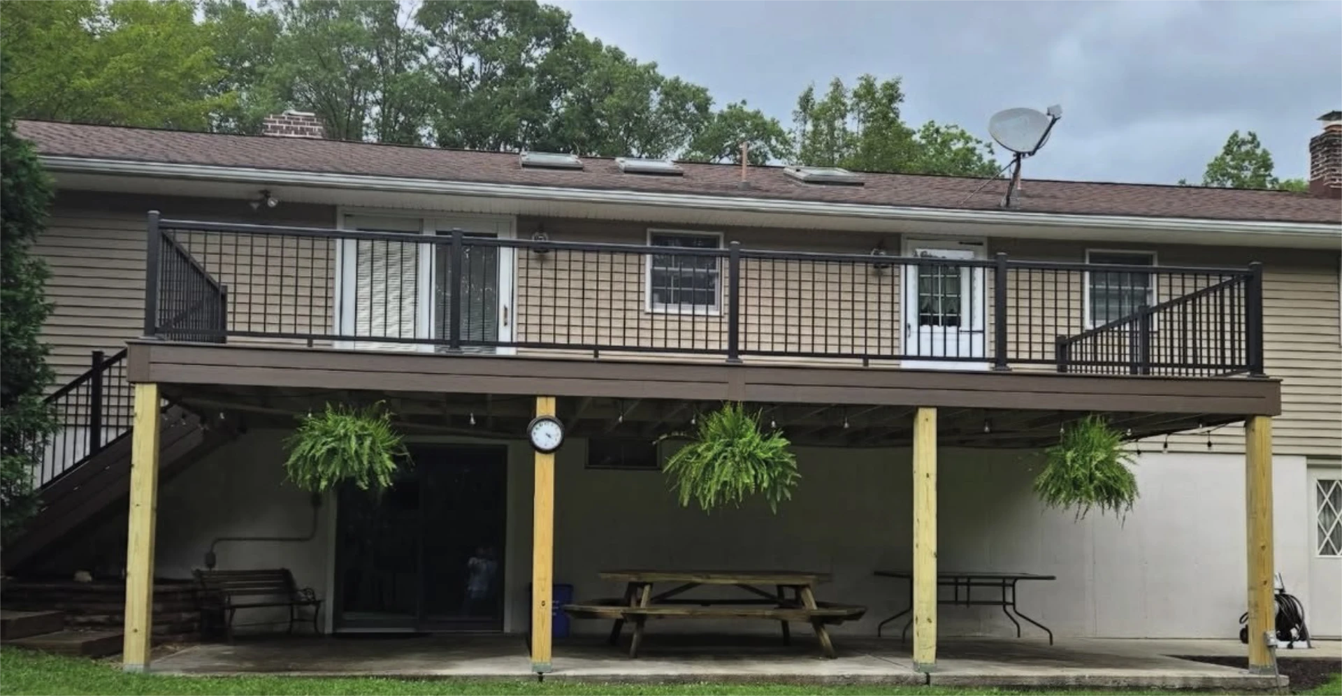 Large raised backyard deck with black railings and covered patio space underneath.