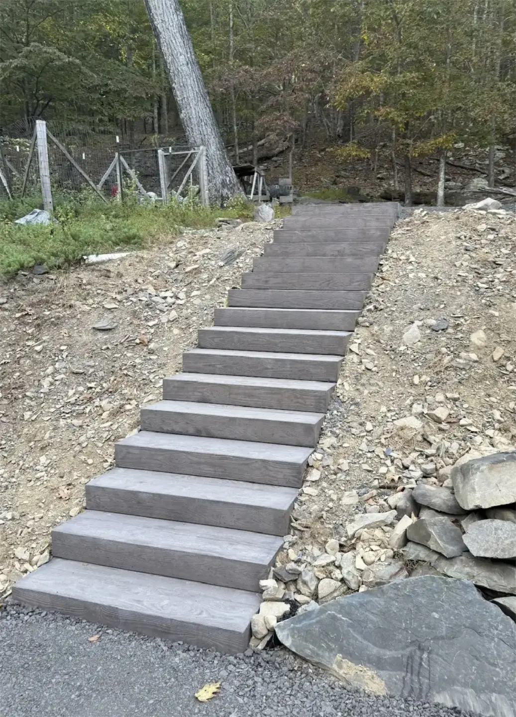 Long hillside staircase with timber look steps through rocky terrain.