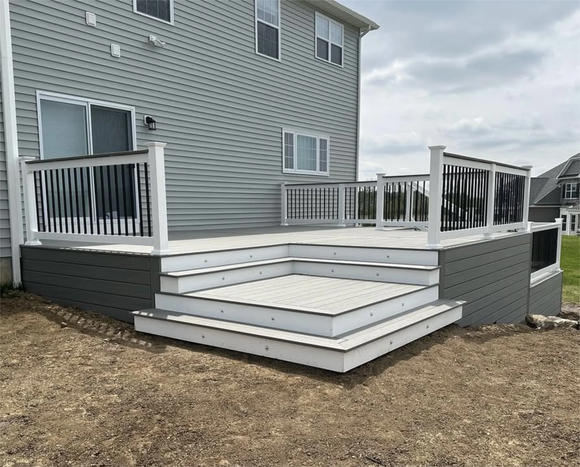 Modern gray composite deck with wide steps and black railing accents.