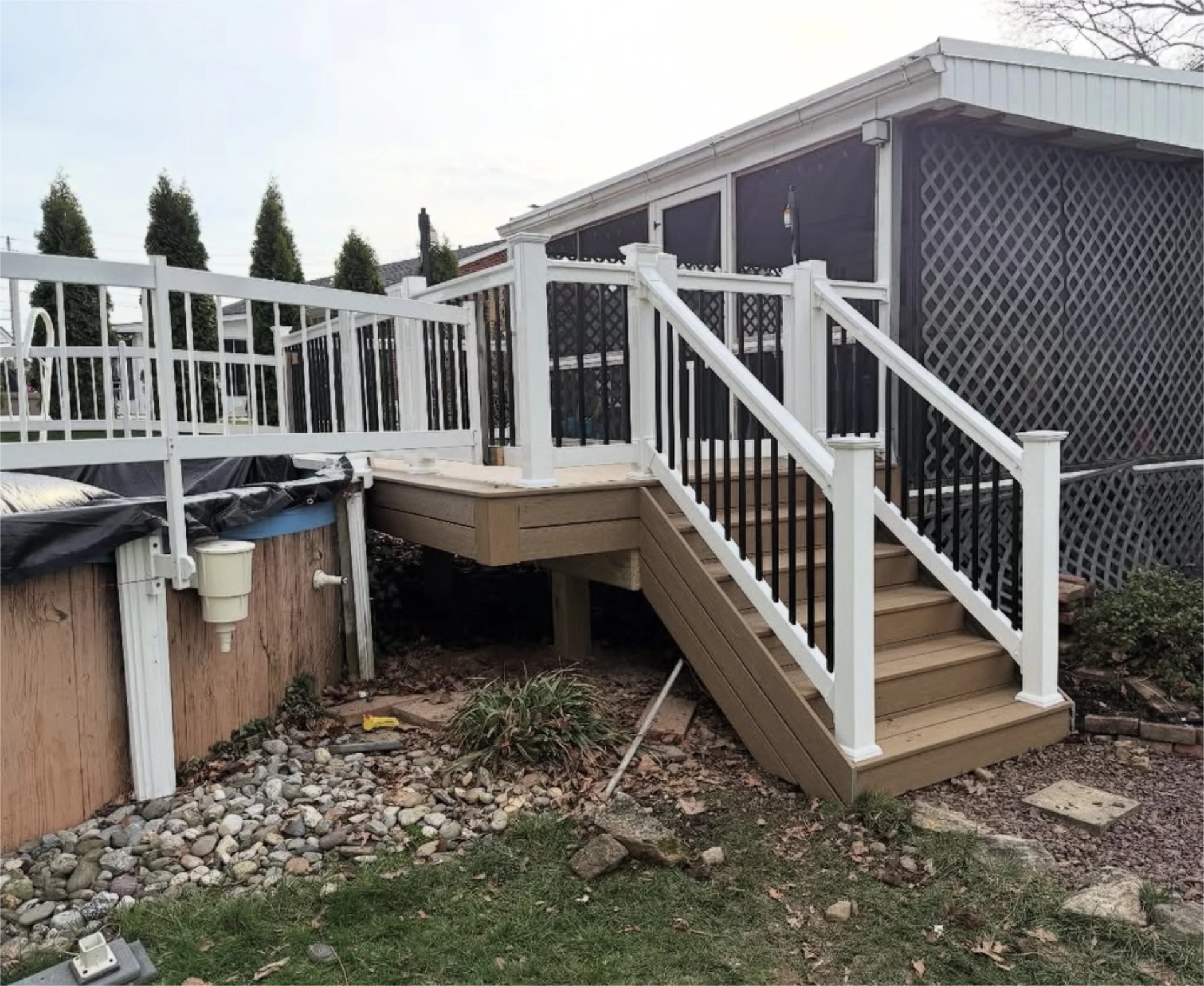 New composite pool deck with white railings and stairs beside screened porch.