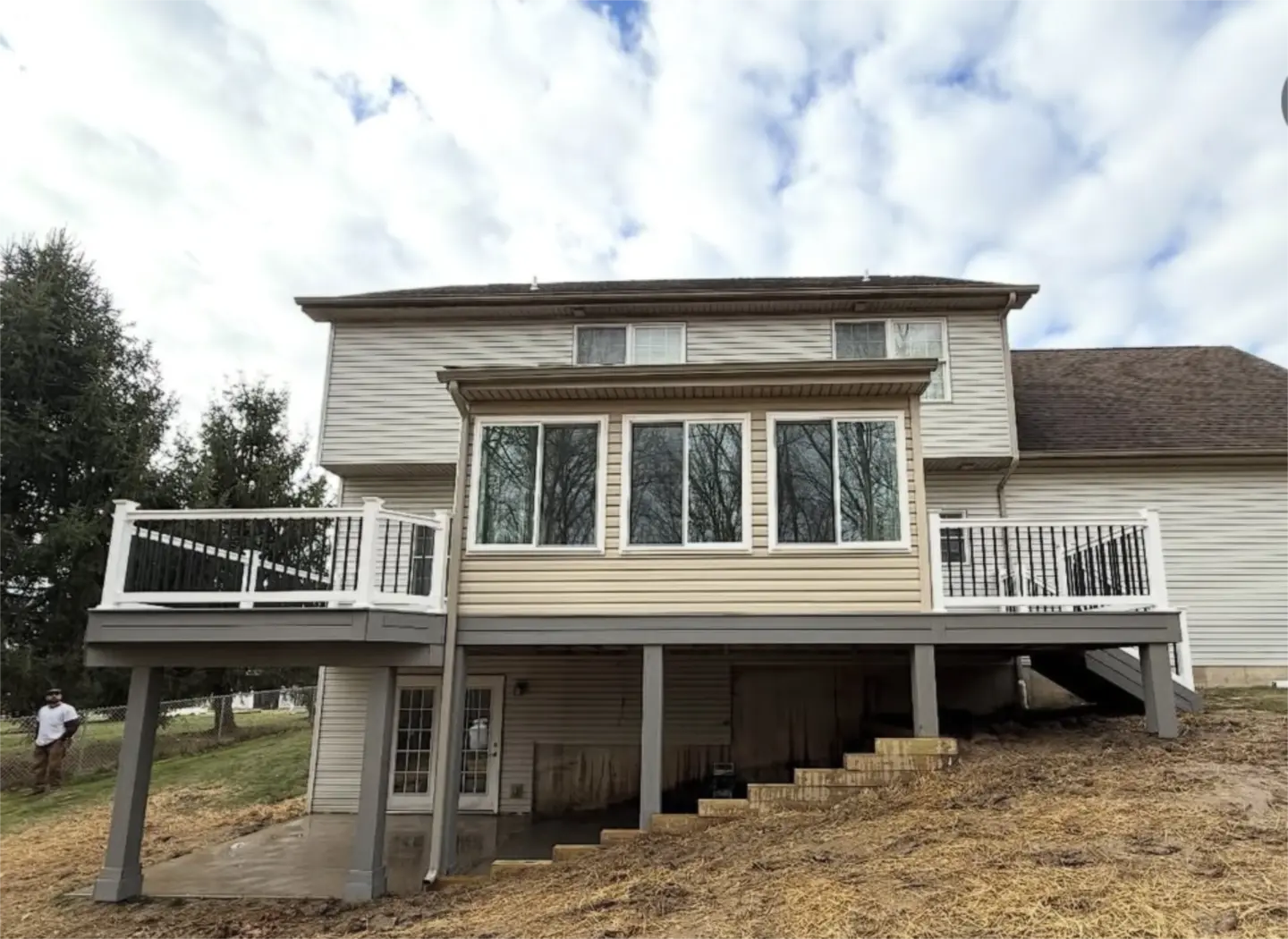 Raised deck and enclosed sunroom behind two story house.