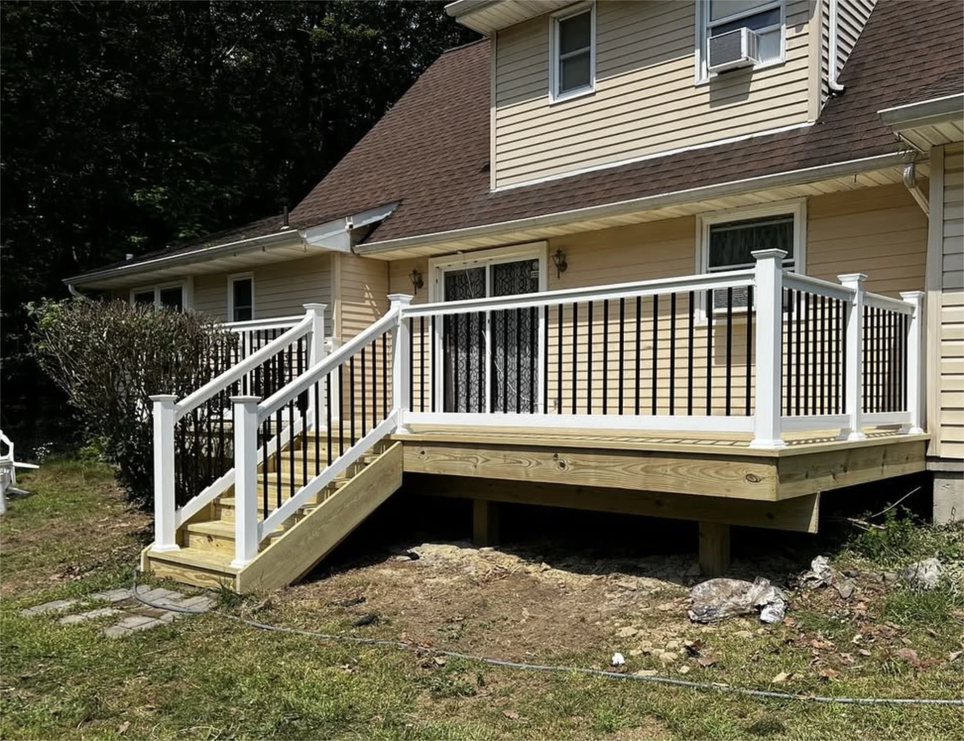 Raised wooden porch with white posts, black railings, and stairs
