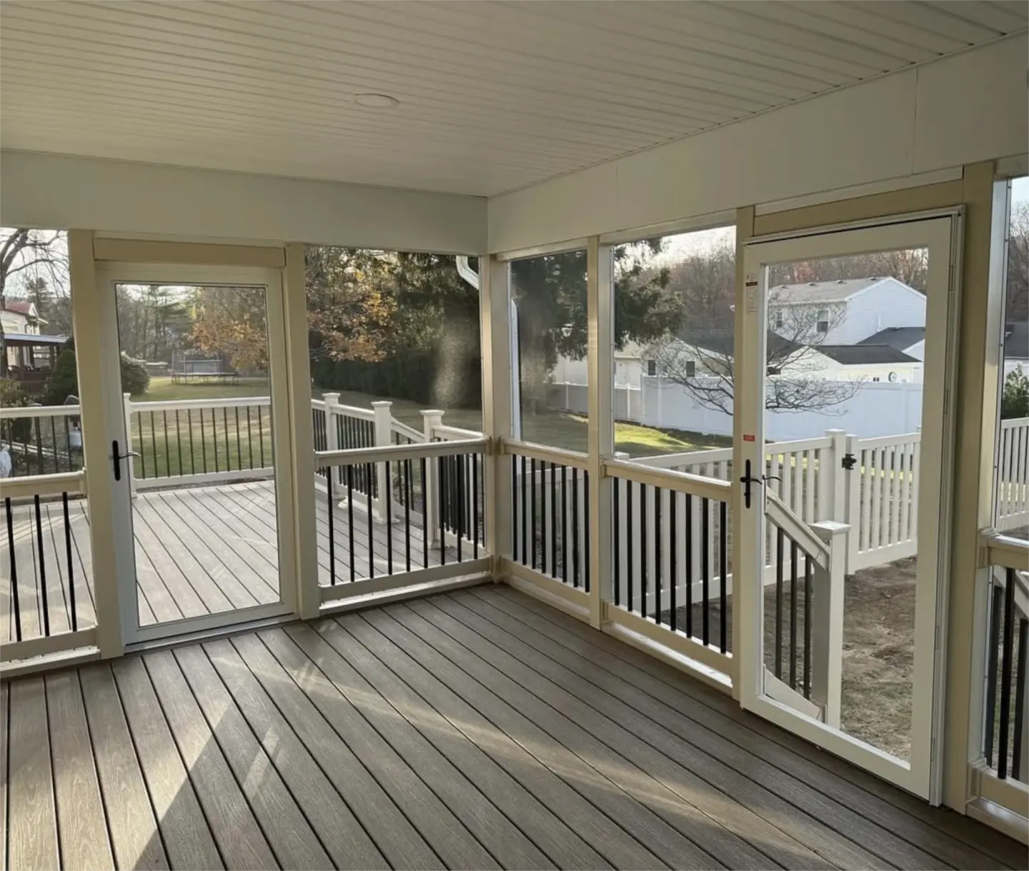 Screened in porch with composite flooring and dual doors.