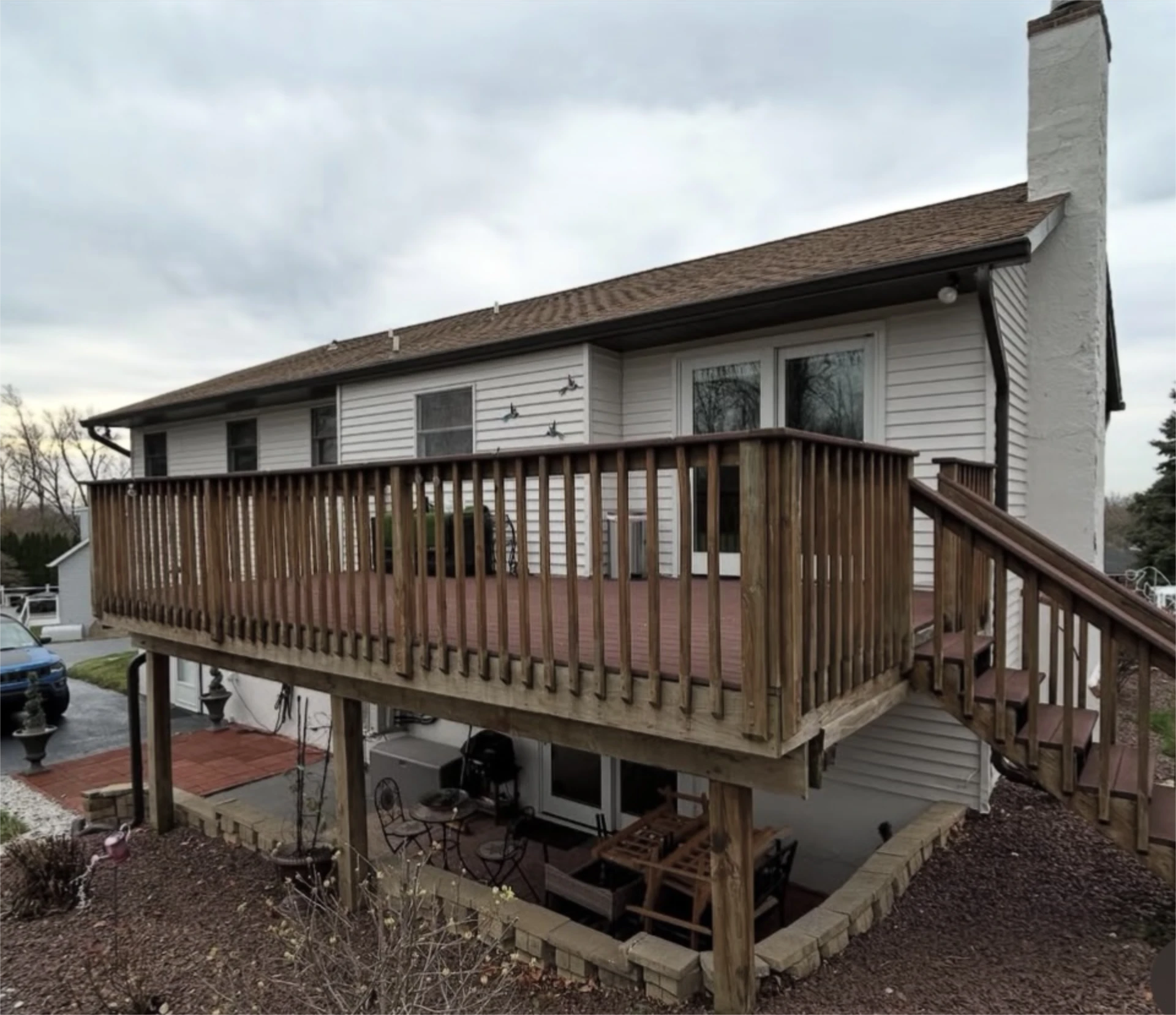 Weathered wooden deck attached to white split level home.