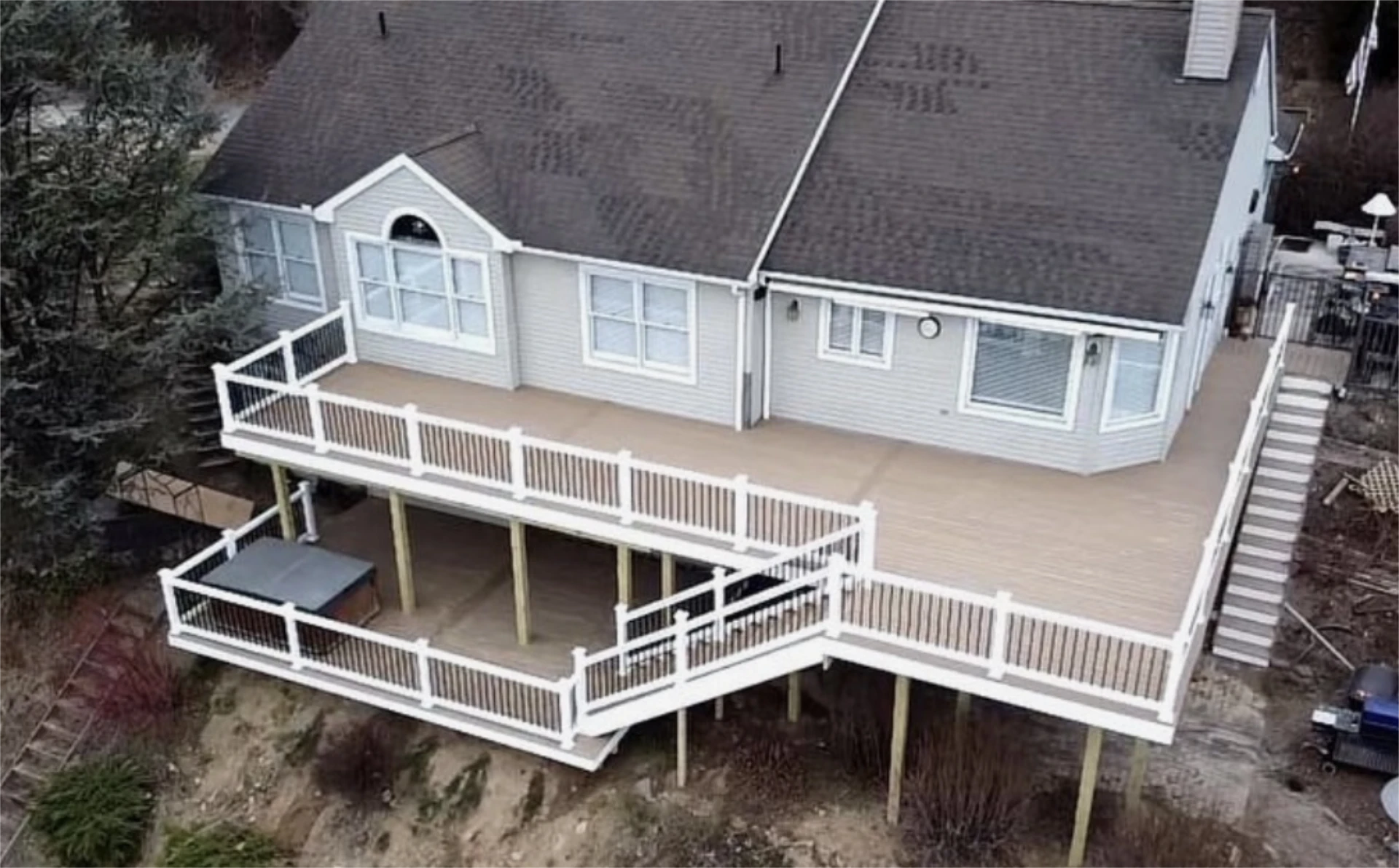 Wraparound elevated deck with white railings on hillside home.
