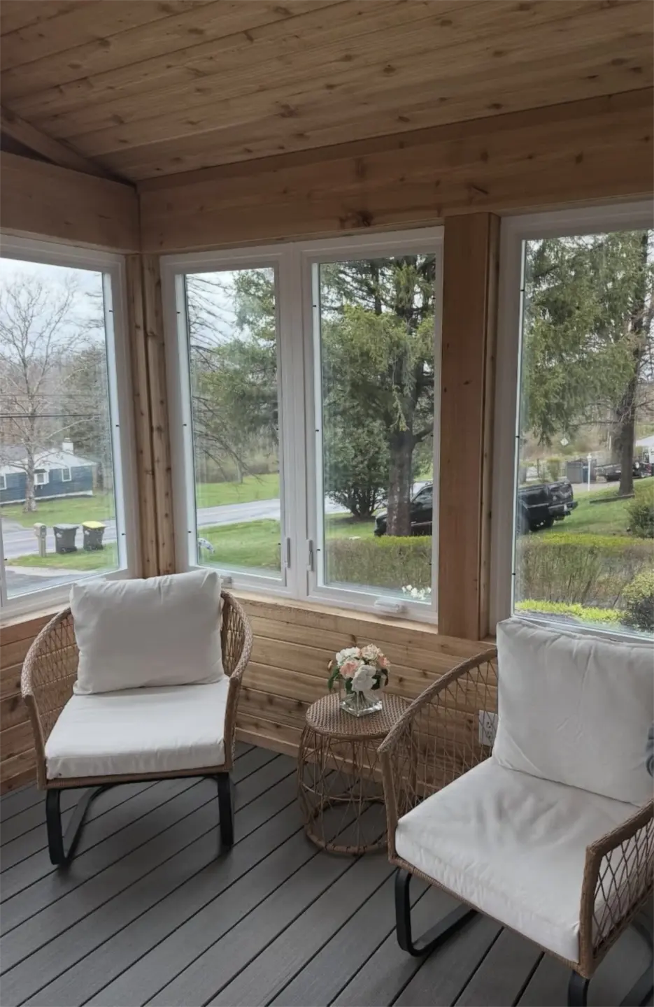 Large windows and Cozy wood sunroom with wicker chairs.